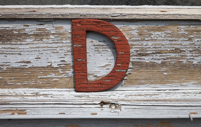 La lettera D in colore rosso attaccata su un'asse di legno